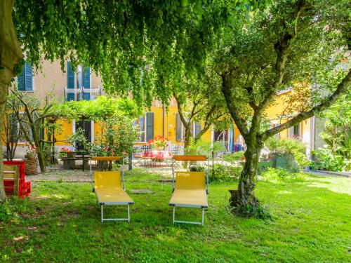 three chairs and a table under a tree in a park at Apartment Angela by Interhome in Dongo
