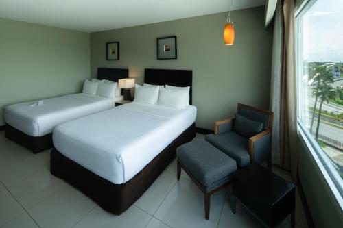a hotel room with two beds and a chair at Crowne Plaza Villahermosa by IHG in Villahermosa