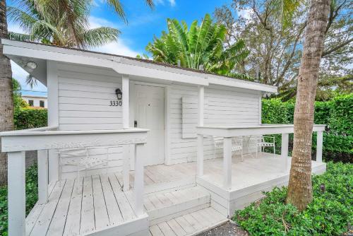 a white building with a porch and a tree at Renovated Grove Bungalow -near Coconut Grove in Miami