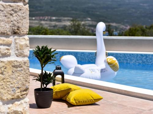 een geel kussen en zwanen op een balkon met een zwembad bij Holiday Home Imperia by Interhome in Pridraga