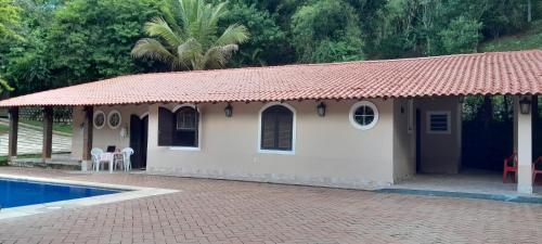 a small house with a tile roof next to a swimming pool at Casa da Gio Penedo in Penedo