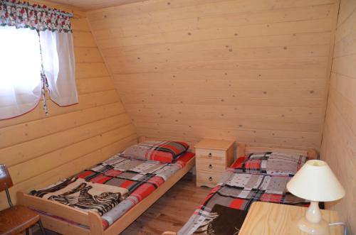two twin beds in a room with wooden walls at Domek przy szlaku in Rajcza