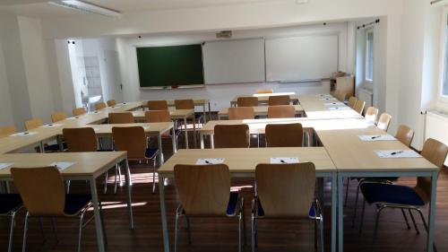 a classroom with tables and chairs and a screen at Waldhotel Brand's Busch in Bielefeld