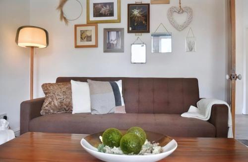 a living room with a couch and a bowl of fruit on a table at Autumn Loft Wyndale Living Malvern Hills in Great Malvern