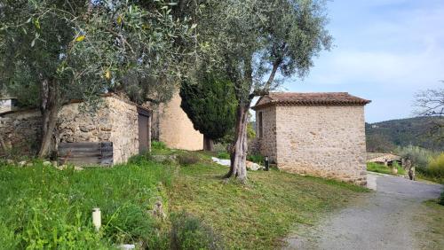a stone building with a tree next to a road at Bastide de Nartas in Tourrettes-sur-Loup