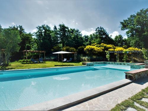 a swimming pool in a yard with a table and an umbrella at Apartment Cipresso by Interhome in Osteria Delle Noci