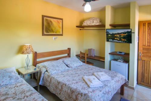 ein Schlafzimmer mit zwei Betten und einem Fernseher an der Wand in der Unterkunft Hospedagem Vila Rica - 500m do centro de Cunha SP in Cunha