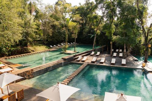 an infinity pool with lounge chairs and umbrellas at Loi Suites Iguazu Hotel in Puerto Iguazú