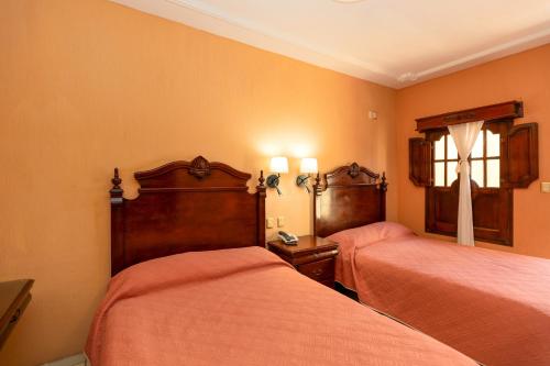 two beds in a room with orange walls at Hotel Casa Dulce Maria in Tequila