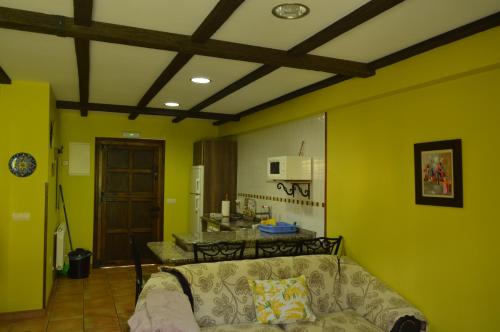 ein Wohnzimmer mit gelben Wänden und einem Sofa in der Unterkunft Apartamentos rurales Casa Rosi in Ranón