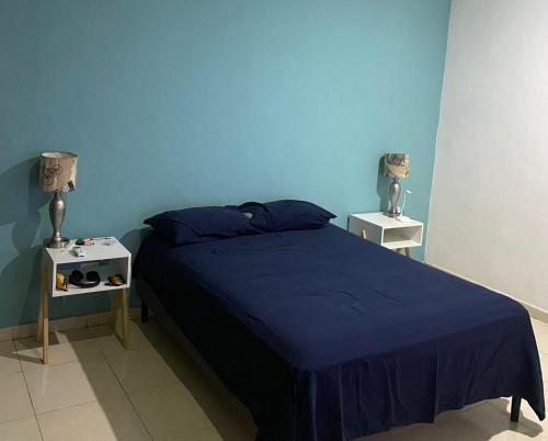 une chambre bleue avec un lit et deux tables de nuit dans l'établissement Casa en el corazón de Playa del Carmen, à Playa del Carmen