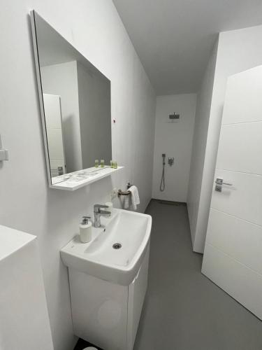 a white bathroom with a sink and a mirror at ALL SEASONS in Feleacu
