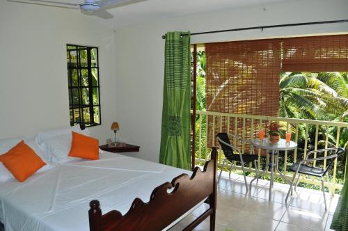 a bedroom with a bed and a balcony with a table at Leatherback Lodge Eco B&B in Salybia