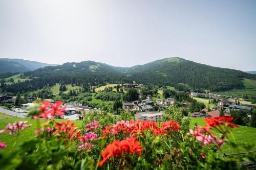 a town in the mountains with flowers in the foreground at Gutzingerhof in Bad Kleinkirchheim