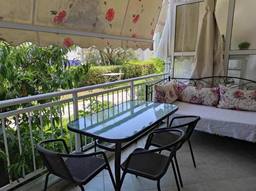 a table and chairs on a balcony with a couch at Studio Aloe in Iraklitsa