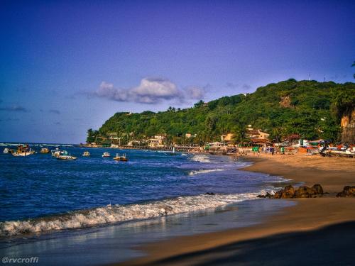 una playa con barcos en el agua y una montaña en Pousada da Pipa, en Pipa