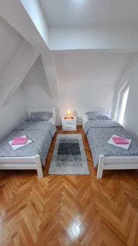 duas camas em um quarto com piso de madeira em Apartman Biser Pive em Plužine
