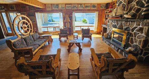 a living room with couches and a stone fireplace at Hotel-Motel Les Voitures d'Eau in L'Isle-aux-Coudres