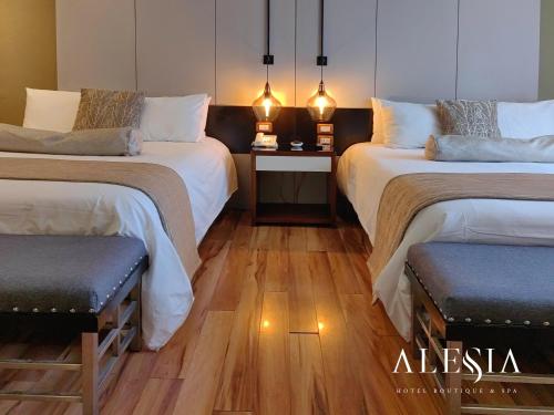 two beds in a room with wooden floors and lights at Alesia - Boutique Hotel & Spa in Aguascalientes