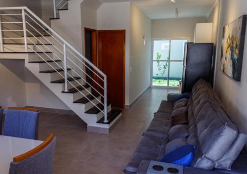 een woonkamer met een bank en een trap bij Serena Beach Triplex in Caraguatatuba