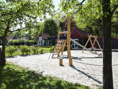 a playground with a wooden swing set in a yard at Holiday Home 4-persoons bos-2 by Interhome in Dalfsen