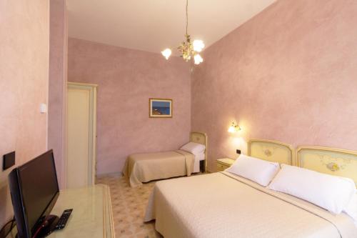 a bedroom with two beds and a desk with a television at Villa Rosa Antico Dimora Storica in Otranto