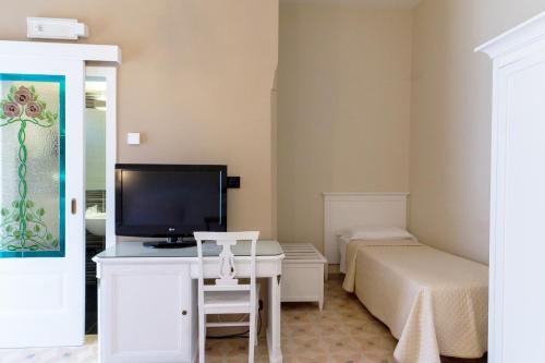 a room with a bed and a desk with a television at Villa Rosa Antico Dimora Storica in Otranto