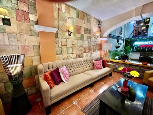a living room with a couch and a stone wall at Hotel del Carmen, en el Centro- DESAYUNO Incluido ! in Tuxtla Gutiérrez