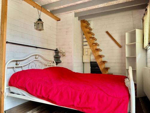 - un lit rouge dans une chambre aux murs blancs dans l'établissement Maison charmante, à Condé-sur-Seulles