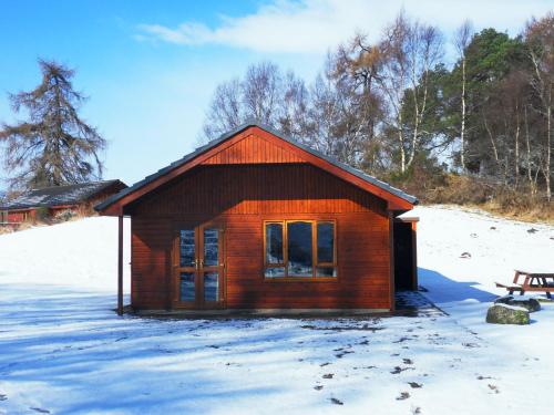 a small wooden cabin in the snow with a bench at Glomach Lodge at Lochletter Lodges in Drumnadrochit