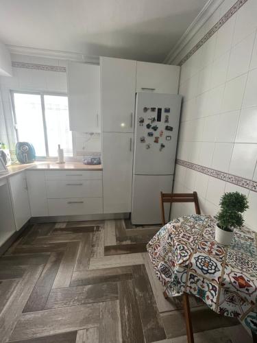 een keuken met een tafel en een witte koelkast bij Lovely Rooms en piso compartido in Sevilla