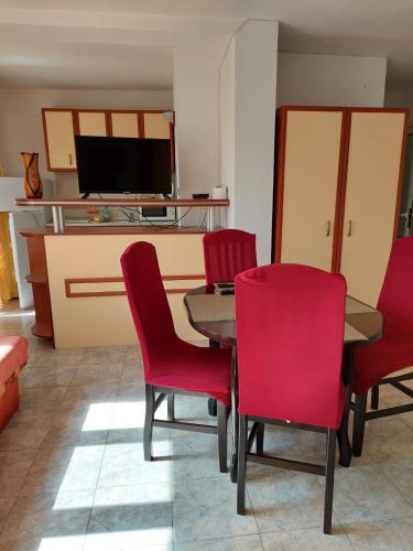 a dining room with a table and red chairs at Къща за Гости "Прохлада" in Sinemorets