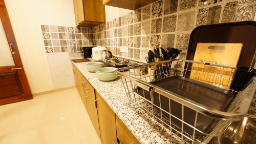 a kitchen counter with a dish drying rack and a sink at Walisons Homestay Abelia in Srinagar