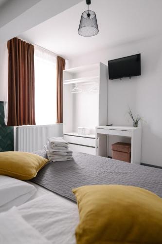a bedroom with a bed with yellow pillows and a television at Pensiunea Sovirag in Praid