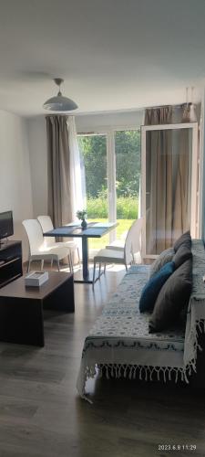 un salon avec un lit, une table et des chaises dans l'établissement Appartement avec piscine près de Honfleur, à Équemauville