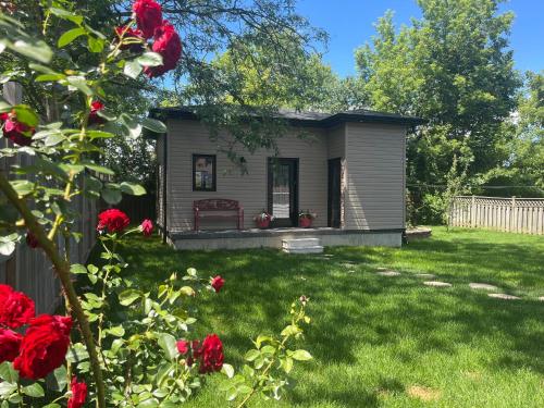 a tiny house in a yard with red roses at The Grassy Oasis in Brampton