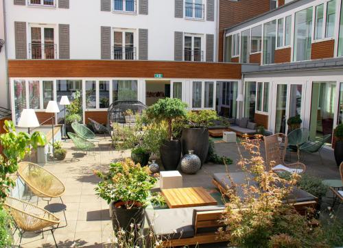 an outdoor patio with chairs and tables and plants at Hotel Ritter Durbach in Durbach