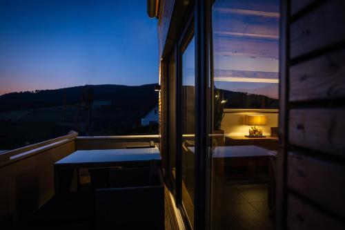 a room with a table and a lamp on a balcony at SAUERLAND CHALETS - "Die Chalets am Bergelchen" in Winterberg