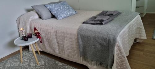 a bed with a gray blanket and a table with a night stand at Cozy studio apartment in the center of Rovaniemi in Rovaniemi