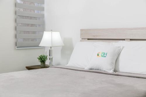 a white bed with a white pillow and a lamp at Choose To Be Happy at Twenty 2A with Pool in Kingston