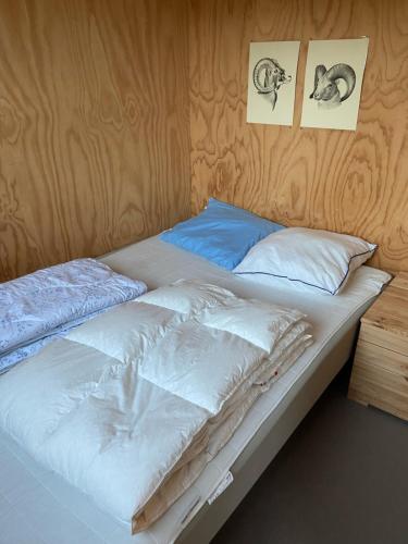 a bed with white sheets and two pictures on the wall at Holme Å Camping & Cottages in Hovborg
