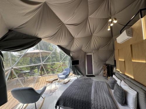 a bedroom in a tent with a bed and chairs at GM Eco Bubble in Yablunytsya