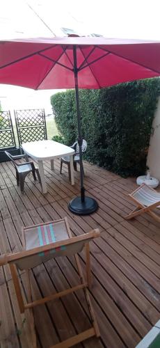 - une table de pique-nique et un parasol sur une terrasse en bois dans l'établissement F2 en rez de jardin, à Cabourg