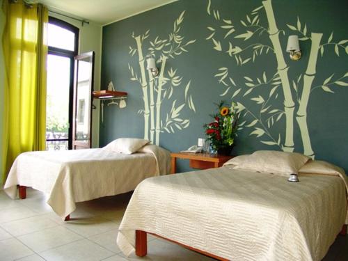 a bedroom with two beds and a green wall at Hotel Plaza Queretaro in Querétaro
