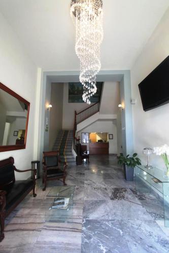 a living room with a chandelier and a staircase at Hotel Plaza Queretaro in Querétaro