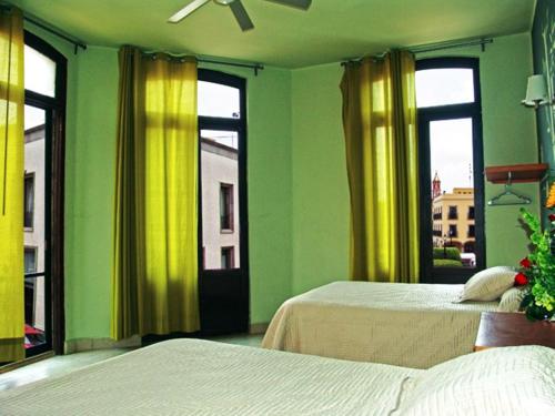 2 camas en una habitación con paredes y ventanas verdes en Hotel Plaza Queretaro, en Querétaro