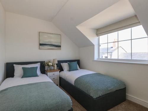 deux lits dans une chambre avec une fenêtre dans l'établissement Belvedere Cottage, à Weymouth