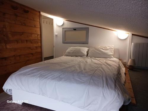 une chambre avec un grand lit blanc avec deux oreillers dans l'établissement Résidence Arandelieres - Beau duplex pour 6 personnes, au coeur de la station d'Arc 1800 MAE-7261, à Arc 1800