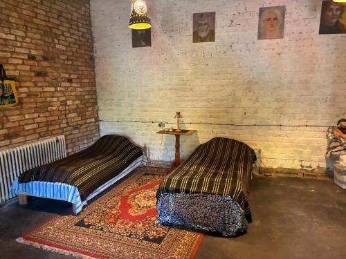 two beds in a room with a brick wall at Gypsy Camp Apartments & Glamping in Liepāja