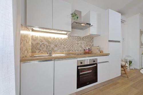 a kitchen with white cabinets and a sink and a stove at Un angolo al sole in Nettuno